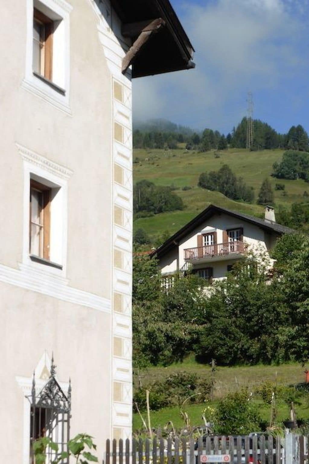 Ein Gebäude mit Balkon und Blick auf einen grünen Hügelhang.