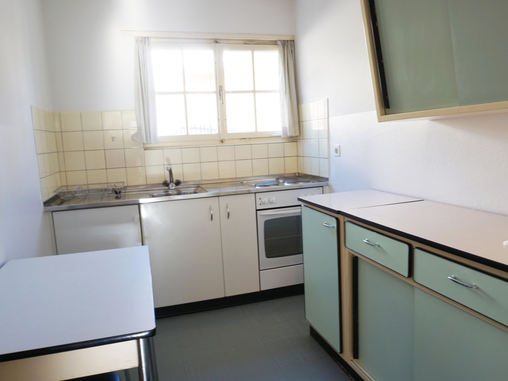 Cocina compacta con ventana, un lavamanos, estufa y armarios.