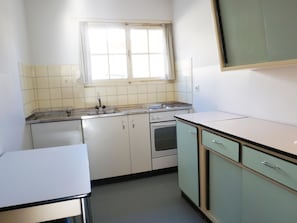 A compact kitchen with a window, a sink, a stove, and cabinets. - Ferienhaus Chasa Allegra, (Scuol) by Interhome (Scuol)