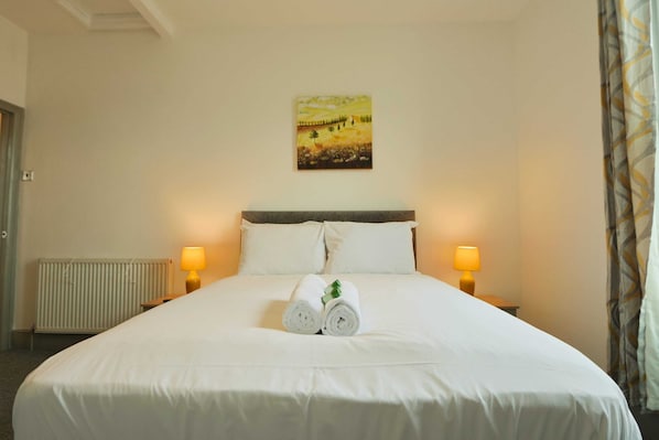 Une chambre d’hôtel avec un grand lit, deux lampes de chevet, un tableau au mur et un radiateur.