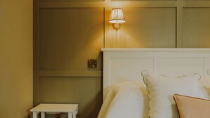 Une chambre d’hôtel avec un lit, une table de chevet et une lampe fixée au mur.