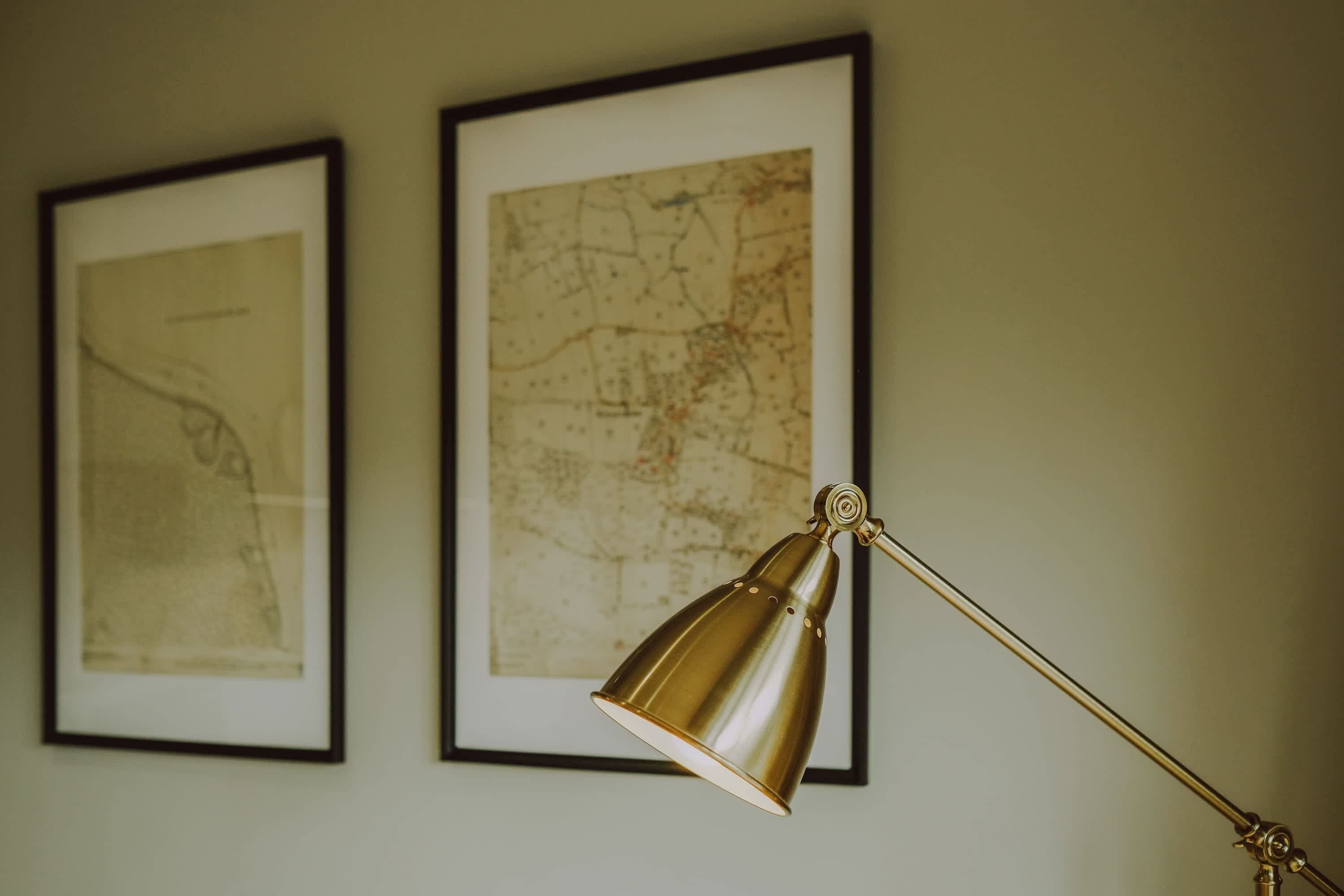 Une carte encadrée et une lampe de bureau en laiton sont accrochées au mur.
