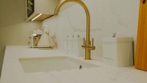 Une cuisine moderne avec un robinet doré, des plans de travail blancs et un évier.