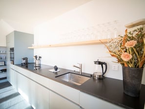 A modern kitchen with a black countertop, stainless steel sink, and a coffee maker. - Chasa Muntanella, (Ftan) by Interhome (Ftan)