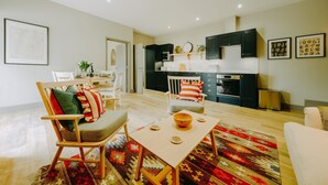 Ein modernes Wohnzimmer mit einem Couchtisch aus Holz, einem gemusterten Teppich und einem Essbereich mit Stühlen und Tisch.