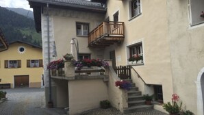 En byggnad med en stentrappa, en träbalkong och blomlådor.