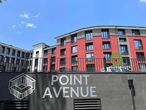 Un edificio con letrero 'POINT AVENUE', de estilo arquitectónico moderno, con varios balcones y ventanas grandes.