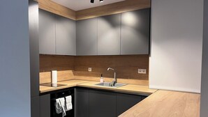 A modern kitchen with grey cabinets, a wooden countertop, and a built-in dishwasher. - 7Mins City Garden and Center+P (Plovdiv)