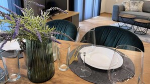 A dining area with a table set for two, a vase with lavender, a TV, and a sofa in the background. - 7Mins City Garden and Center+P (Plovdiv)