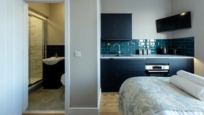 Una habitación de hotel moderna con ducha, lavamanos y una cama con colcha estampada.