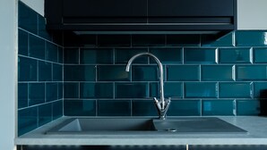 Una cocina con un lavamanos moderno, gabinetes negros y azulejos de protector contra salpicaduras color aguamarina.