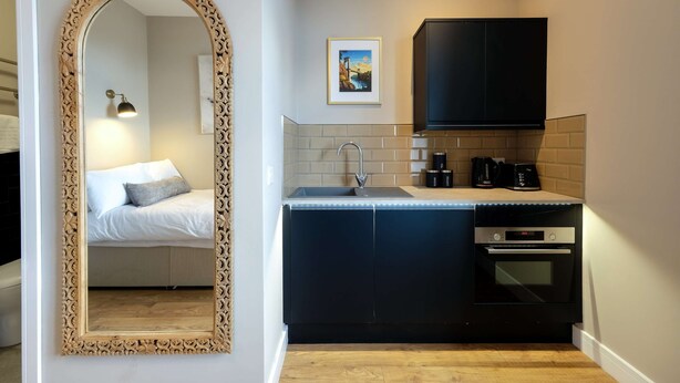 A compact kitchen with a built-in oven, a coffee maker, and a framed picture on the wall.