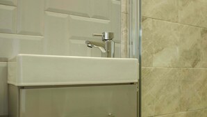 Un baño con ducha, lavamanos y puerta.