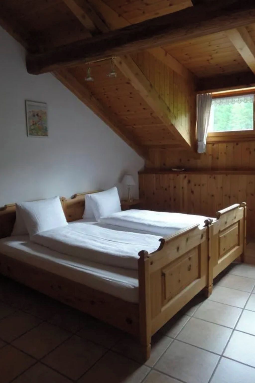 Une chambre à coucher avec un lit en bois, une literie blanche et un plafond en pente.