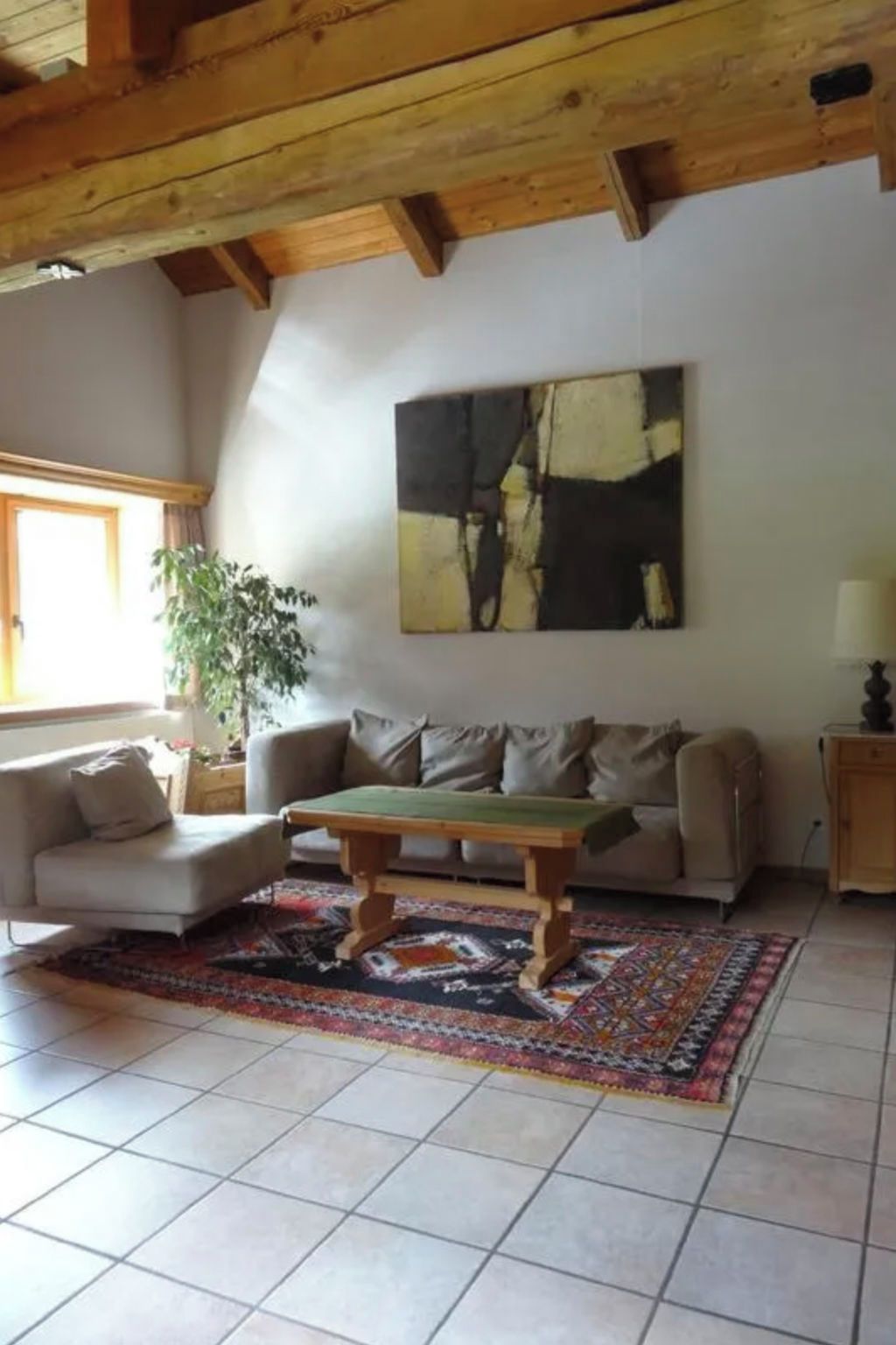 Ein Wohnzimmer mit einer Couch, einem Couchtisch, einem Bild an der Wand und einer Topfpflanze.