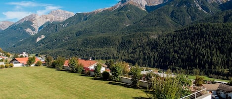 A residential area with houses, a green lawn, and mountains in the background.