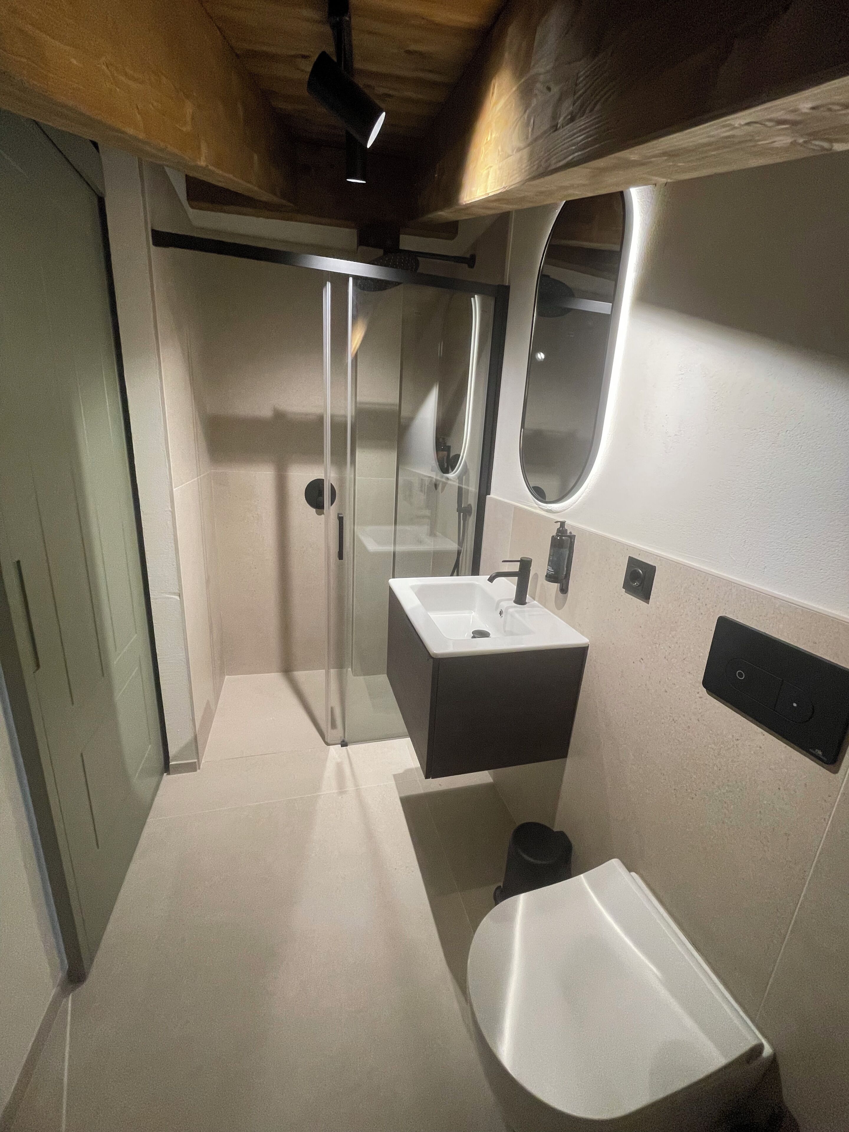A modern bathroom with a glass-enclosed shower, a sink, and a toilet.