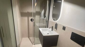 A modern bathroom with a glass-enclosed shower, a sink, and a toilet.