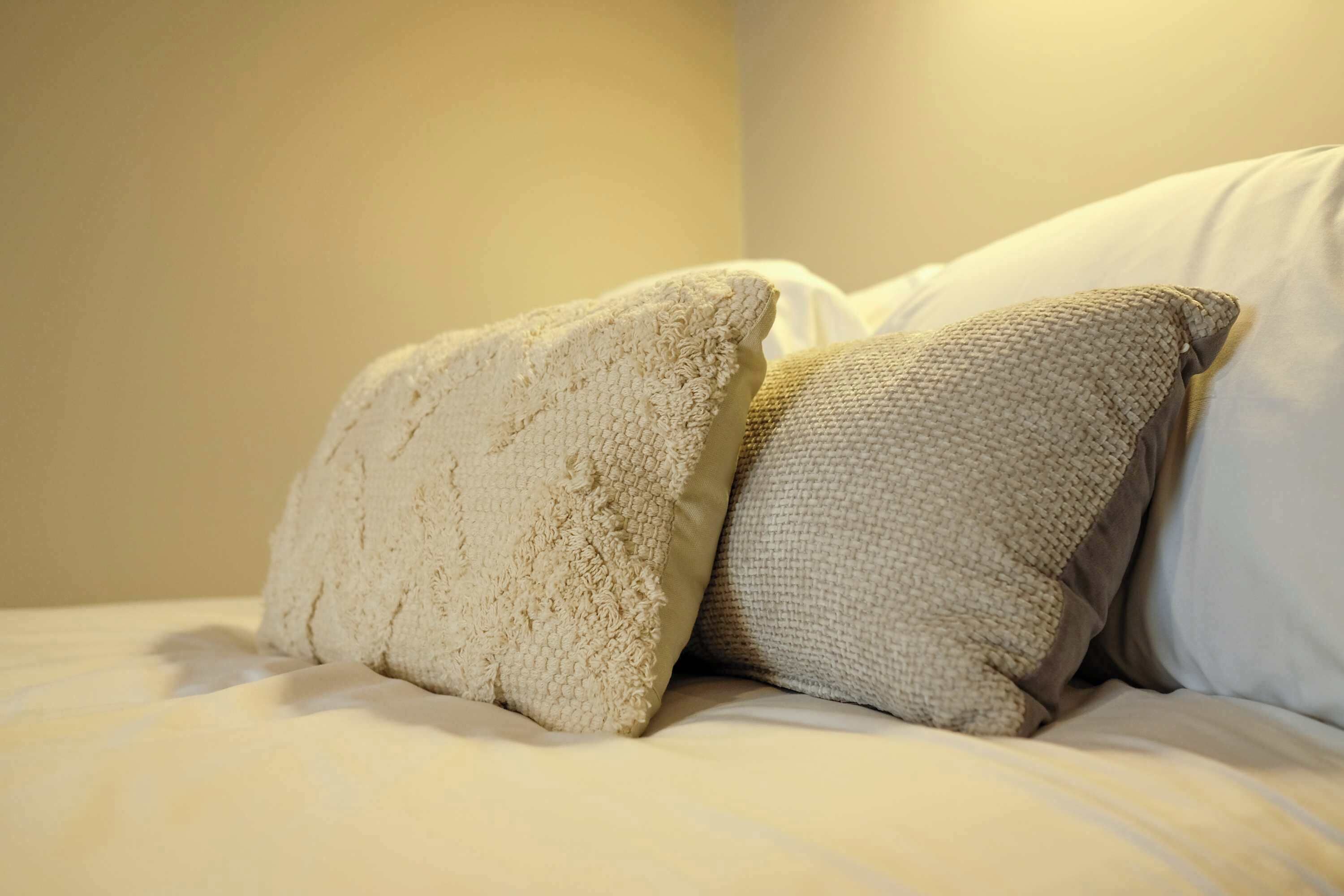 Una cama con dos almohadas y un sábana blanca.