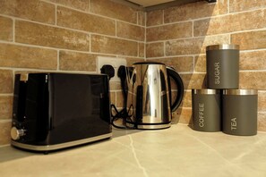 A kitchen counter with a toaster, a kettle, and two stainless steel tumblers labeled 'SUGAR' and 'COFFEE.' - The Willow - Studio 11 (Patchway)