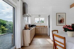 A modern kitchen with wooden cabinets, a built-in stove, and a large window.
