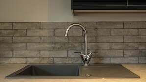 Eine Küche mit modernem Wasserhahn, einem rechteckigen Spülbecken und einer Wandverkleidung aus Ziegelsteinen.