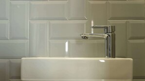 Ein Badezimmer mit einem weißen Waschbecken und einem Chromarmaturen.