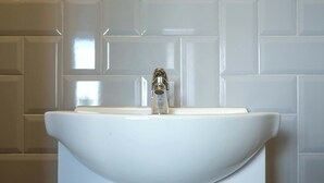 A bathroom with a white sink, a faucet, and a tiled wall. - The Willow - Studio 23 (Patchway)