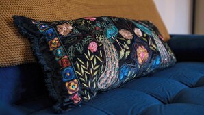 Un divano blu con un cuscino decorativo caratterizzato da ricami.
