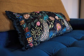 Ein blaues Sofa mit einem Zierkissen mit aufgestickten Motiven.