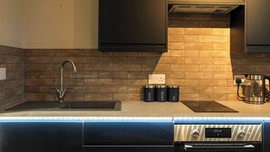 Una cucina moderna con lavastoviglie integrata, cappa aspirante in acciaio inossidabile e pannello di fondo in mattoni.
