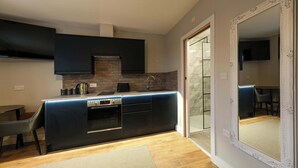 Une cuisine moderne avec des meubles de couleur sombre, un four encastré et un coin repas avec une chaise.