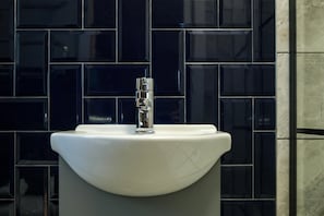 Ein Waschbecken mit chromfarbenem Wasserhahn vor einer gefliesten Wand.