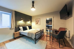 Ein Schlafzimmer mit Bett, Nachttisch, Stuhl und einem kleinen Tisch mit Sitzgelegenheit.