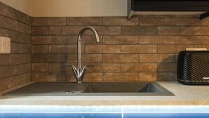 A kitchen with a modern faucet, a sink, and a tiled backsplash. - The Willow - Studio 27 (Patchway)