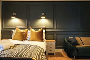 Ein Schlafzimmer mit einem Bett, Nachttischen, einem Beistelltisch und einem grünen Sofa.