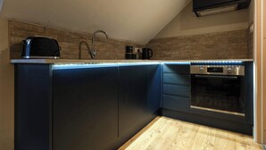 A modern kitchen with a built-in oven, a coffee maker, and a toaster. - The Willow - Studio 33 (Patchway)