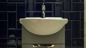 A bathroom with a white sink, a chrome faucet, and a tiled wall. - The Willow - Studio 33 (Patchway)