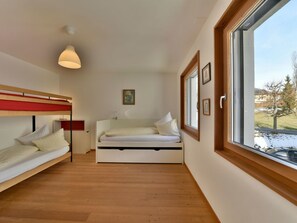 Una stanza compatta con un letto a castello, un letto singolo, una lampada a sospensione e una finestra vista all'esterno.