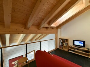 A spacious living area with a red sofa, a television, and a bookshelf. - CRAISTA 8, (Scuol) by Interhome (Scuol)