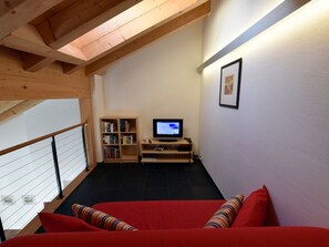 A cozy room with a red sofa, a television, and a bookshelf. - CRAISTA 8, (Scuol) by Interhome (Scuol)