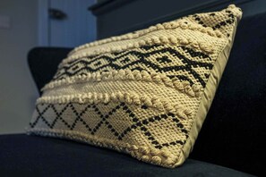 En kudde med en tydlig struktur och ett mönster, placerad på en soffa i en mörk färg.
