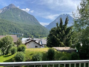 A mountainous landscape with a village, houses with solar panels, and a clear sky.