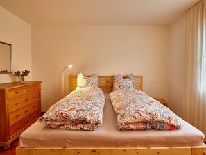 A room with two beds, a wooden dresser, a mirror, and a lamp.