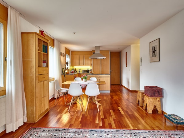 A spacious kitchen with wooden cabinets, a dining area with a table and chairs, and a patterned rug on the floor.