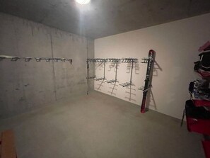 A room with a ski rack against the wall and a ski leaning against it.
