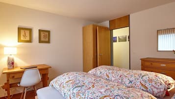 Une chambre à coucher comprenant un lit, un bureau, une chaise, une armoire et une table de chevet.