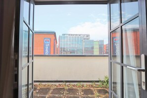 A view through a window with a clear sky, a building with a Travel logo, and a brick wall. - St Thomas one bedroom flat (Bristol)