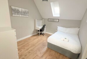 A bedroom with a bed, desk, chair, and a painting on the wall. - Four Bedroom Apartment in Fantastic Location (Bristol)