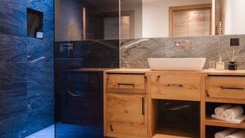 Ein modernes Badezimmer mit großem Spiegel, einem Haubenwaschbecken, Holzschränken und einer Duschkabine aus Glas.